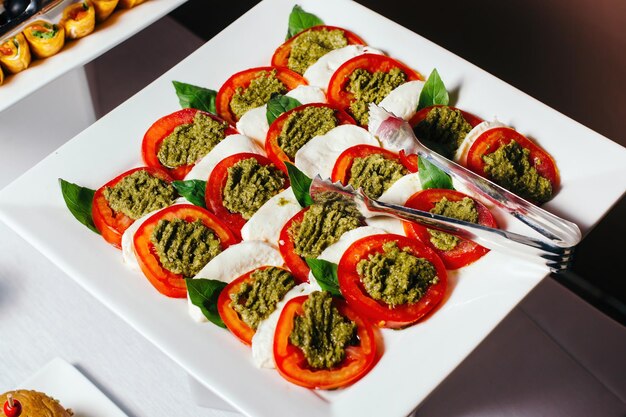 Traditionele italiaanse caprese geserveerd op een bord gesneden tomaten met pesto