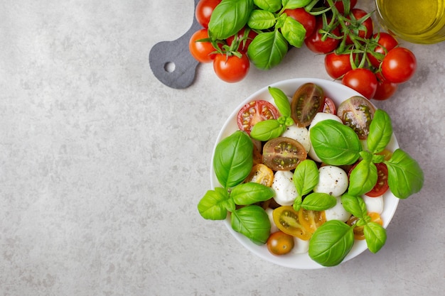 Traditionele Italiaanse caprese salade met cherrytomaatjes, mozzarella, basilicum, olijfolie, kruiden en zeezout