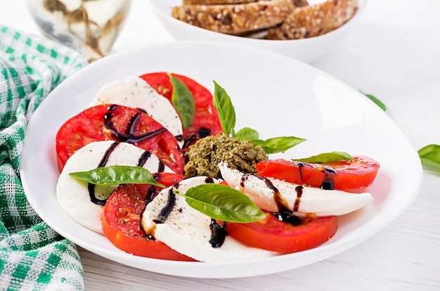 Traditionele italiaanse caprese salade met mozzarella, tomaat, basilicum en balsamico azijn