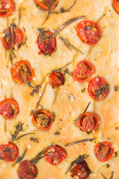 Traditionele italiaanse focaccia brood textuur met tomaten en rozemarijn in mentale bakplaat