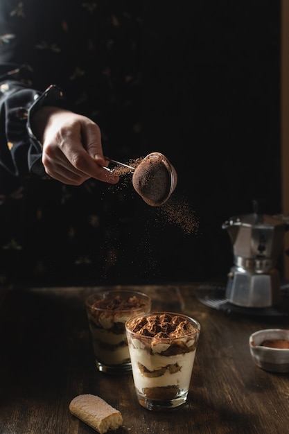 Foto traditionele italiaanse huisgemaakte tiramisu met mascarpone en cacaopoeder in beweging