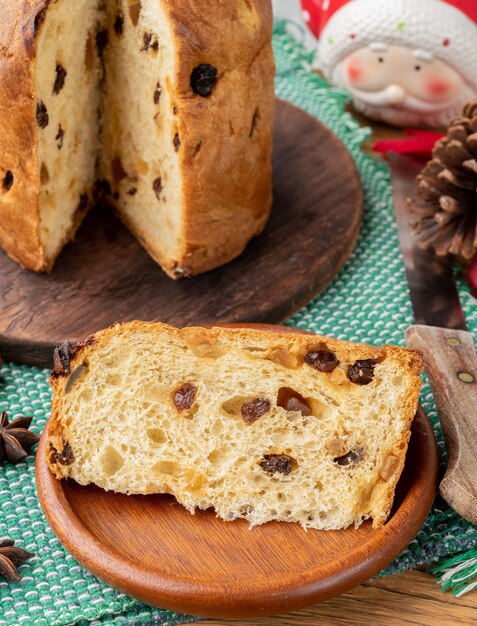 Traditionele Italiaanse kerst fruitcake panettone met plakje op een bord.