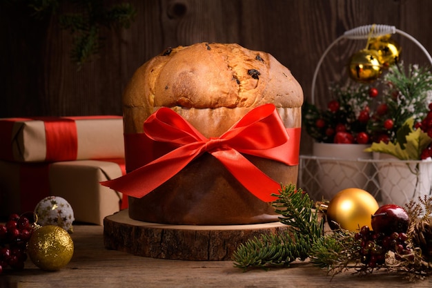 Traditionele italiaanse kerstcake panettone met rode strik en feestelijke decoratie op houten rustieke