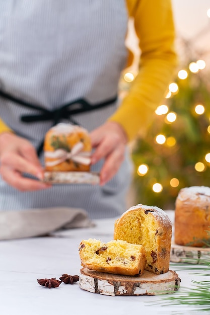 Traditionele Italiaanse kersttaart panettone op een rustieke tafel vrouwelijke handen houden taart vast
