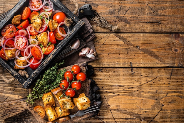 Traditionele italiaanse panzanella-salade met tomatenui en brood croutons in houten dienblad houten achtergrond bovenaanzicht kopieer ruimte