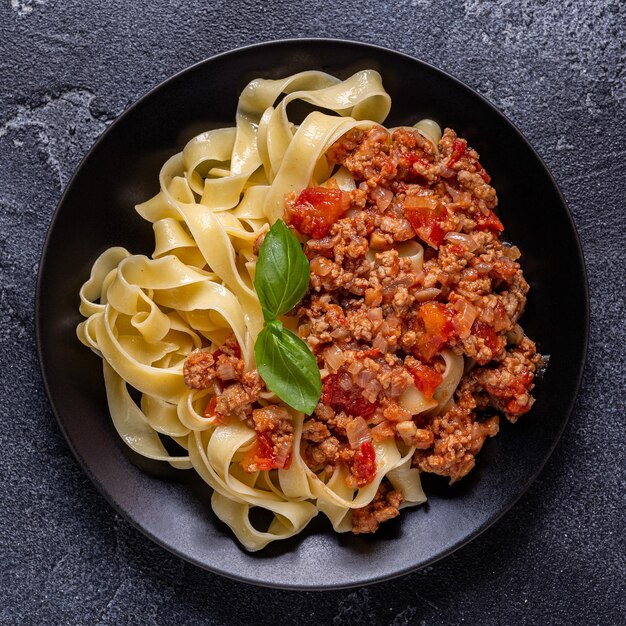 Foto traditionele italiaanse pasta bolognese op een zwarte plaat