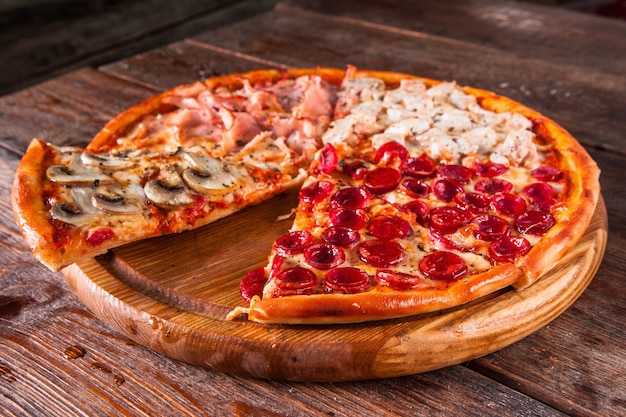 Traditionele italiaanse pizza met champignons, brom, kip en worstjes met gesneden plak geserveerd op houten tafelblad. Menufoto.