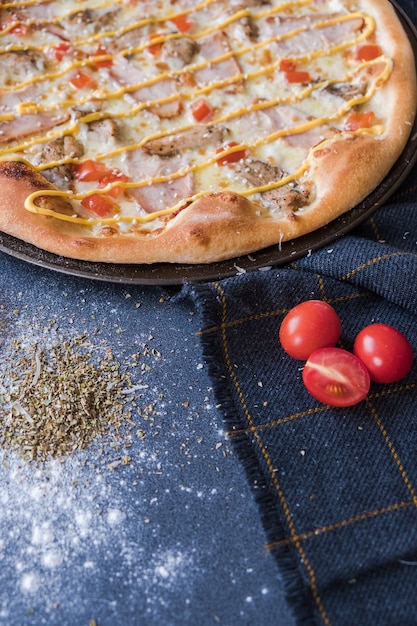 Traditionele italiaanse pizza met chiken, ham op donkerblauwe stenen tafel