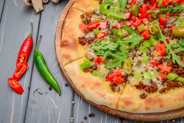 Traditionele Italiaanse pizza met gehakt op houten tafel