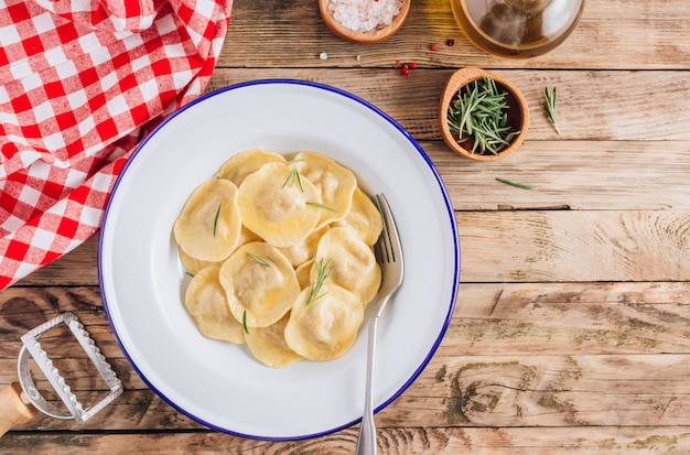 Traditionele Italiaanse ravioli met rozemarijn en parmezaan geserveerd op een geëmailleerde borden