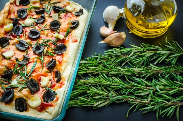 Traditionele Italiaanse vegetarische focaccia van zelfgebakken brood met olijven, rozemarijn