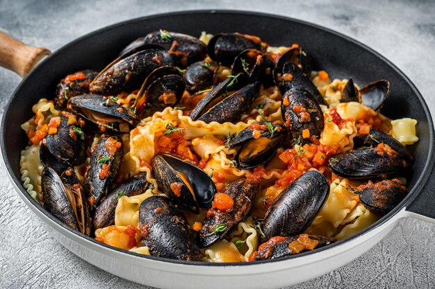 Traditionele Italiaanse zeevruchtenpasta met mosselen, spaghetti en tomatensaus. Witte achtergrond. Bovenaanzicht.