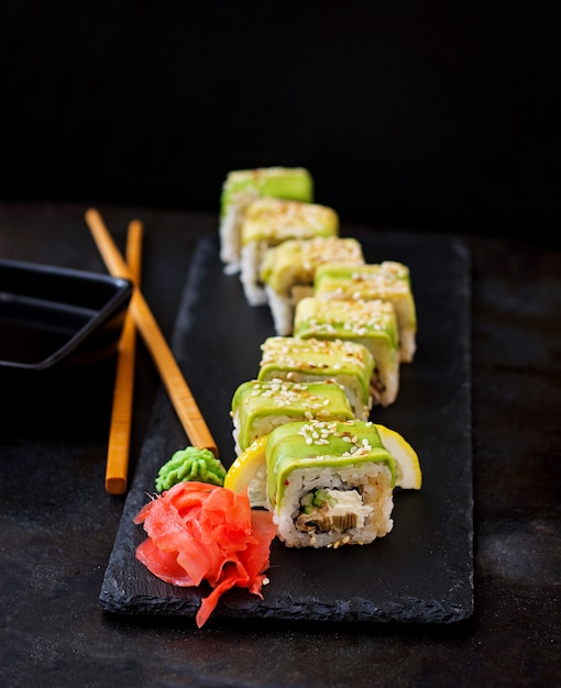 Traditionele japanse gerechten - sushi, broodjes en saus op een zwarte tafel.