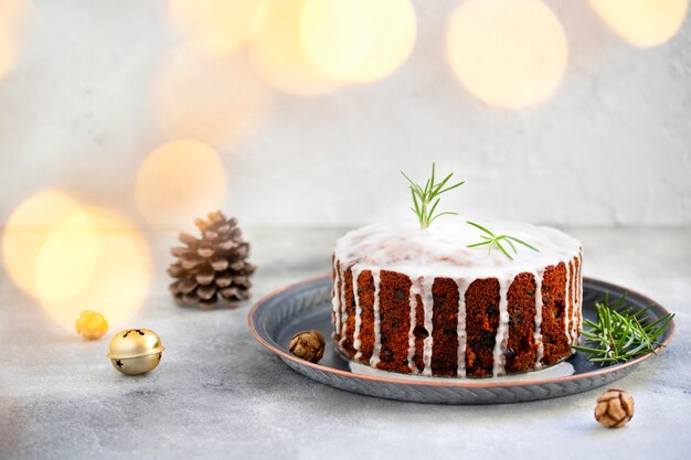 Foto traditionele kerst cake met fruit en noten op een lichte tafel en lichte achtergrond. dessert voor de wintervakantie. kerstversiering en verlichting. kopieer ruimte
