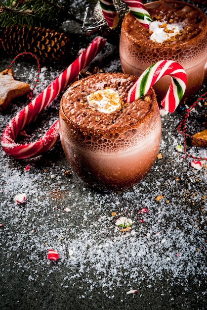 Traditionele kerstdranken. Noordpoolcocktail met snoepgoed, snoep, pepermunt, warme chocolademelk of cacao, gember en melk. Donker, met kerstdecoratie,