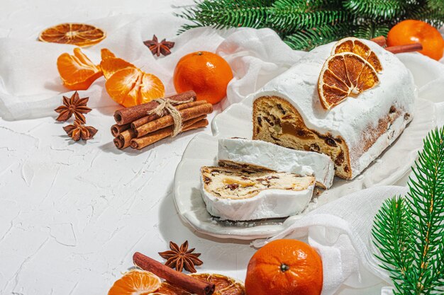 Traditionele kerststollen Duitse cake Europees gebak geurig zelfgebakken brood met kruiden en gedroogd fruit Xmas boomtakken en decoraties witte achtergrond kopie ruimte