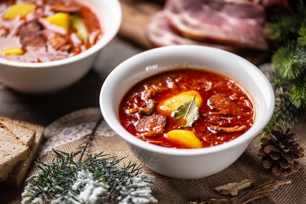 Traditionele kerstzure koolsoep met aardappelworst, gerookt varkensvlees en champignons