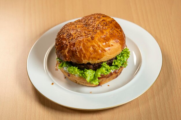 Traditionele klassieke burger geserveerd op een wit bord op een zwarte achtergrond Vlees hamburger plat gelegd