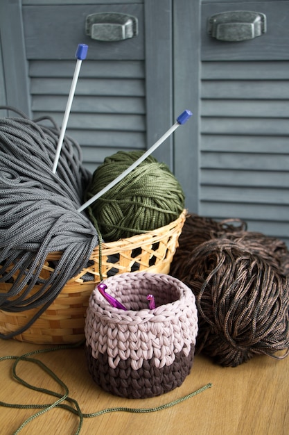 Traditionele kleurrijke garens voor hobby breien in een mand van stroeco op een lichte houten oppervlakte.