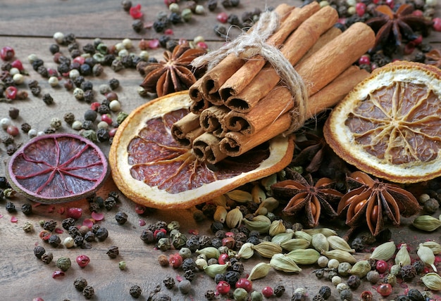 traditionele kruiden voor glühwein. kaneelstokjes, anijs sterren, kardemom, peper en droge citrusvruchten op een houten tafel.