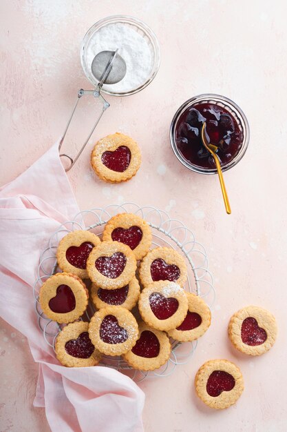 Traditionele Linzer cookie met aardbeienjam en poedersuiker op roze mooie achtergrond bovenaanzicht zelfgemaakte Oostenrijkse zoete dessert eten op Valentijnsdag vakantie snack concept