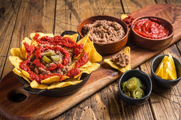 Traditionele Mexicaanse minder bonen met nachos jalapeno en tomatensaus Houten achtergrond Bovenaanzicht