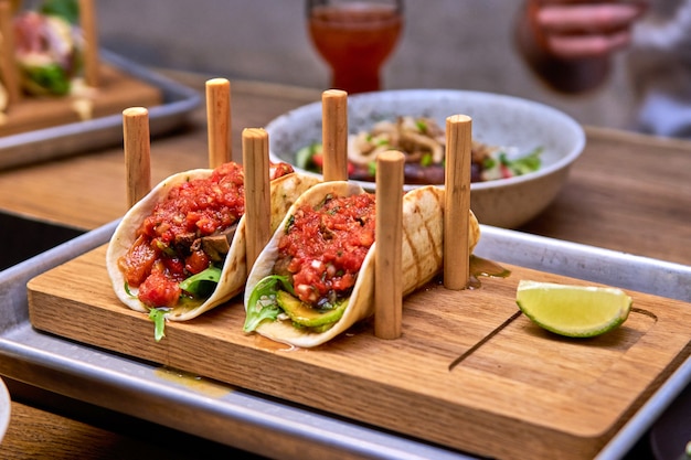 Traditionele mexicaanse straatvarkentaco's met rundvlees, tomaten, avocado, chili en uien in gele maïstortilla genaamd al pastor