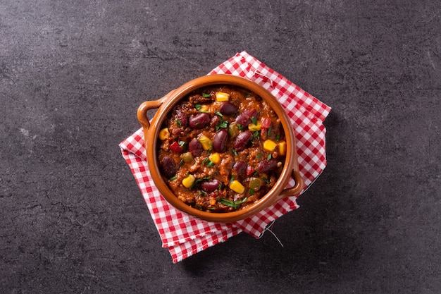 Traditionele Mexicaanse tex mex chili con carne in een kom op zwarte achtergrond.