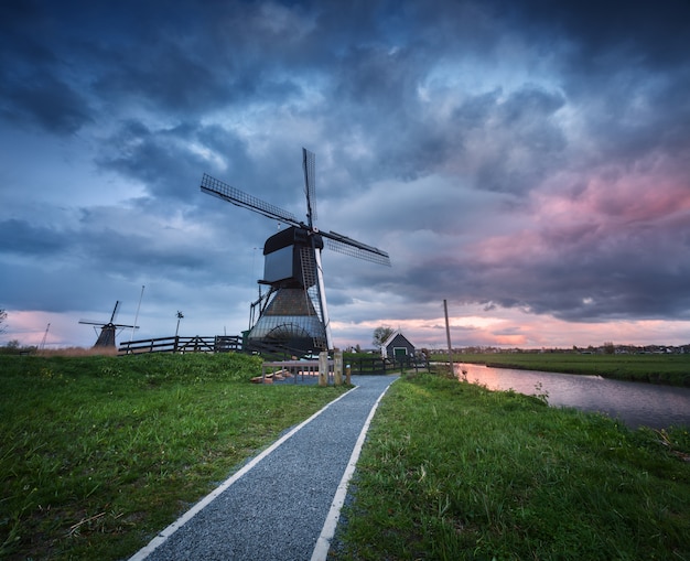 Traditionele Nederlandse windmolens dichtbij waterkanalen met bewolkte hemel, landschap