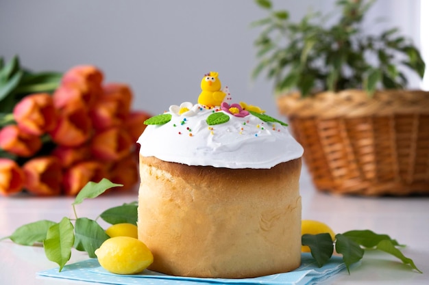 Foto traditionele oekraïense paascake met glace-suikerglazuur en lentedecoratie oranje tulpen op de achtergrond vrolijk pasen recept van paasbakkerij feestelijk gebak voor de lentevakantie