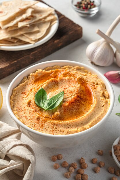 Traditionele oosterse hummus met olijfolie, sesam en paprika op een grijze achtergrond