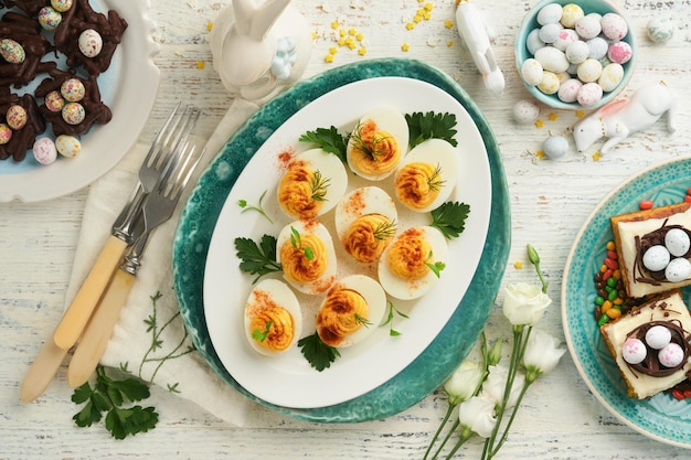 Traditionele paasbrunch of -diner met gevulde eieren met paprika-worteltaartrepen en chocoladenestcakes met geglazuurde walnoteneieren Paasmaaltijdgerechten met decoraties Bovenaanzicht plat gelegd