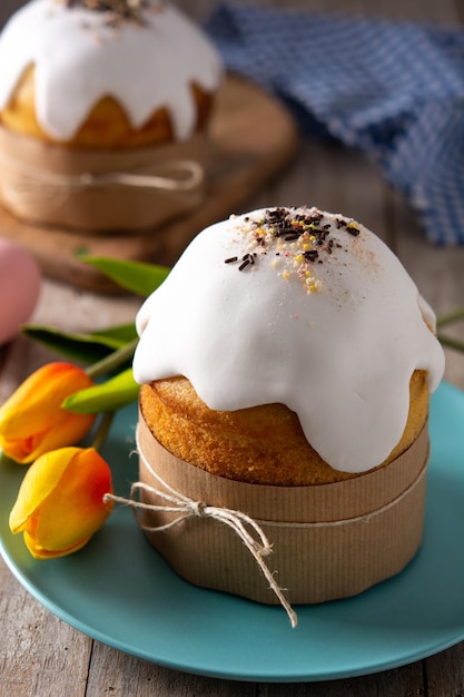 Traditionele paascake, kleurrijke eieren en tulpen op houten tafel.