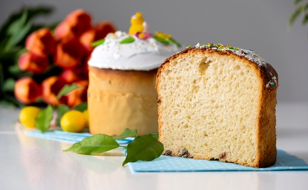 Traditionele paascake met wit glazuur en lentedecoratie oranje tulpen op de achtergrond Vrolijk Pasen Recept van paasbakkerij Feestelijk gebak voor de lentevakantie