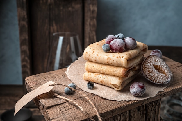 Traditionele pannenkoeken met bevroren bessen op een sfeervolle vintage achtergrond.