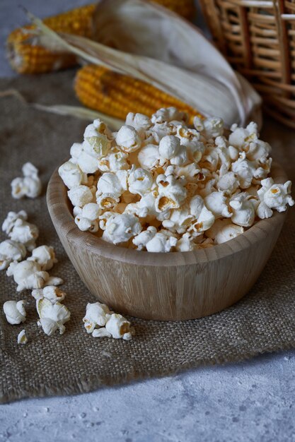 Traditionele popcorn in een houten kom en maïskolven op de tafel.