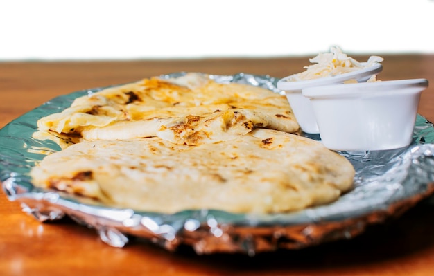 Traditionele pupusas geserveerd met salade op tafel Twee Nicaraguaanse pupusas met salade op tafel Zijaanzicht van heerlijke Salvadoraanse pupusas met kaas geserveerd op tafel