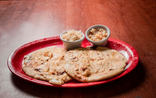 Traditionele pupusas geserveerd op een houten tafel Close-up van Nicaraguaanse pupusas geserveerd op houten tafel Heerlijke traditionele Salvadoraanse Pupusas met gesmolten kaas op houten tafel