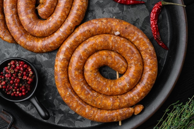 Traditionele rauwe spiraal varkensworst op zwarte houten tafel achtergrond bovenaanzicht plat lag