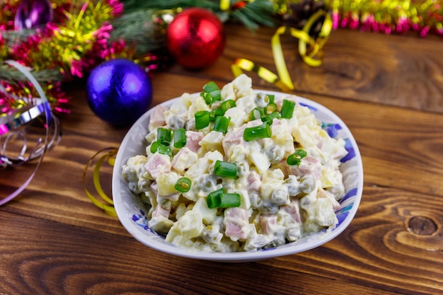 Traditionele Russische feestelijke salade Olivier en nieuwjaarsversieringen op houten tafel