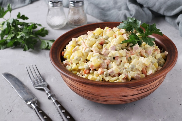 Traditionele Russische feestelijke salade Olivier in kom tegen grijze oppervlakte, Close-up, horizontaal formaat