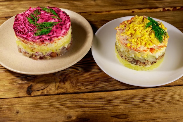 Traditionele Russische gelaagde salades "Mimosa" en "haring onder een bontjas" (shuba) op houten tafel