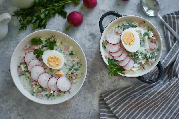 Traditionele Russische koude okroshka-soep geserveerd in een bord met kruiden en ei Kefir groentesoep