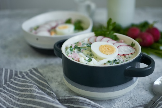 Traditionele Russische koude okroshka-soep geserveerd in een bord met kruiden en ei Kefir groentesoep