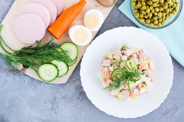 Traditionele Russische meer olivier salade op een plaat en ingrediënten voor zijn preparationin hoogste mening