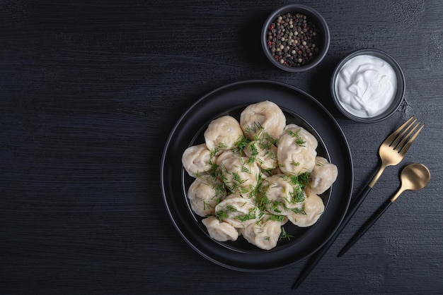 Traditionele Russische pelmeni ravioli dumplings met vlees op zwarte achtergrond Bovenaanzicht