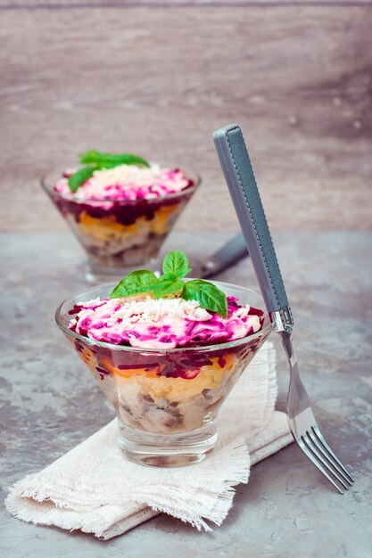 Traditionele Russische salade, haring onder een bontjas in kommen en vork op de tafel.