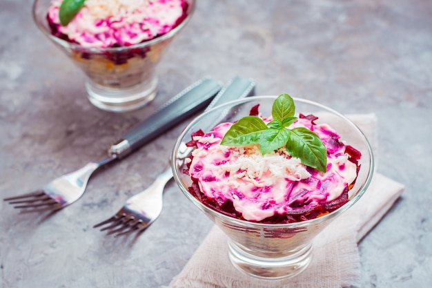 Traditionele Russische salade, haring onder een bontjas in kommen en vorken op de tafel.