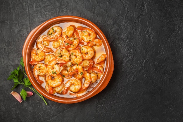 Traditionele spaanse garnalen met knoflook en peterselie op een donkere achtergrond