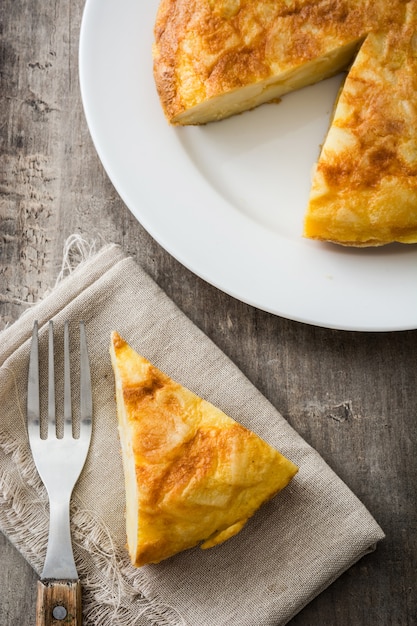 Traditionele Spaanse omelet en vork op de houten mening van de lijstbovenkant